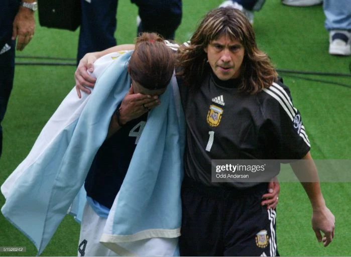 Burgos consuela a su compañero Mauricio Pochettino, hoy entrenador de primer nivel, tras la eliminación de Argentina en primera ronda del Mundial de Corea y Japón 2022.